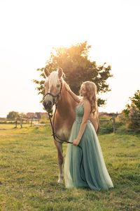 Pferdefotografie: Junge Frau im Abendkleid steht neben ihrem Pferd